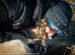 First place musher Kristy Berington gives one of her dogs a kiss. [Photo by Albert Marquez/Planet Earth Adventures]